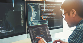 Developer working on software at a multi-screen workstation